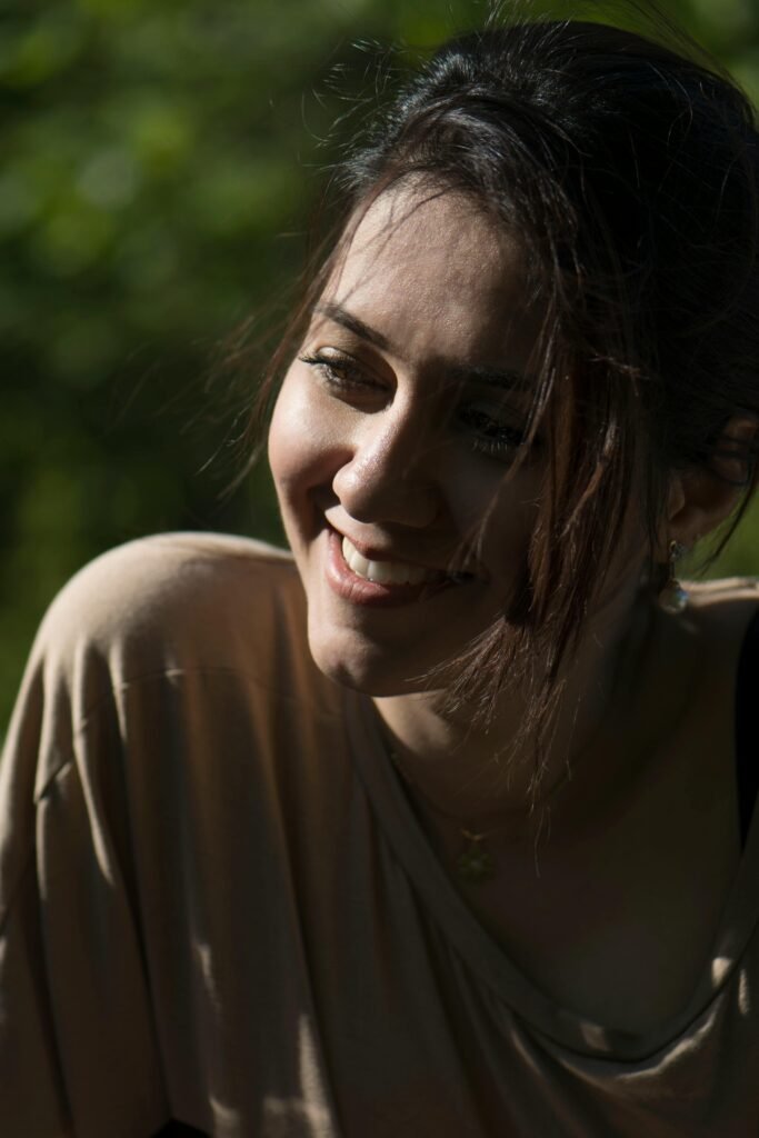 A joyful woman enjoying the sunlight outdoors, captured in natural lighting.