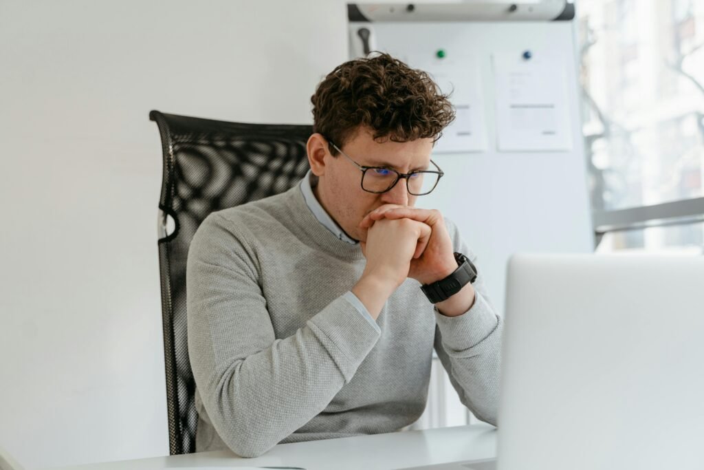 A thoughtful businessman wearing glasses, engaged in work at the office.